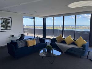 uma sala de estar com sofás, uma mesa e janelas em The Kinson em Melbourne