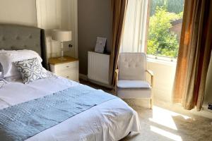 Stunning 3 bedroom Victorian home near Pollok country park في غلاسكو: غرفة نوم بسرير وكرسي ونافذة