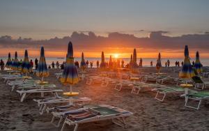 um grupo de cadeiras e guarda-sóis numa praia em BlancoHouse - Sul Parco em Riccione