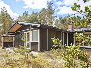 a black house in the middle of a forest at Holiday home Aakirkeby II in Vester Sømarken