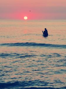 a person sitting in a boat in the ocean at sunset at Camper Niklas in Vama Veche