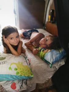 dwoje małych dzieci leżących na łóżku w obiekcie Camper Niklas w mieście Vama Veche