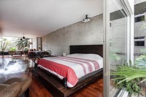 Un dormitorio con una cama grande y una pared de hormigón en Destination Condesa @Tamaulipas Loft, en Ciudad de México