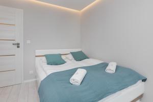 a white bedroom with a bed with towels on it at Stunning Apartment Hokejowa with Terrace & Parking by Renters in Gdańsk
