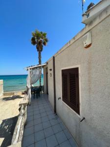 um edifício na praia com uma palmeira ao fundo em Appartamento sul mare em Noto Marina