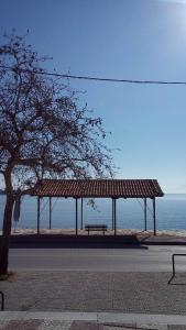 um banco sentado sob um pavilhão ao lado do oceano em Dream House em Agria