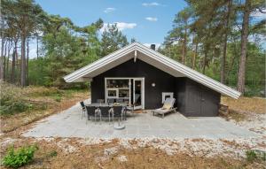 un cobertizo negro con una mesa y sillas delante en Beautiful Home In Nex With Sauna, en Vester Sømarken