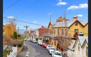 una calle en una pequeña ciudad con coches aparcados en The Glebe Cottage, en Hobart