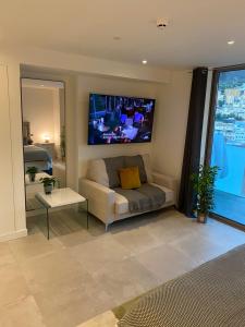a living room with a couch and a tv on the wall at Ardwyn Studio Apartments Gibraltar in Gibraltar