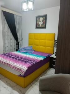Un dormitorio con una cama amarilla y morada y una silla en بورتو سعيد, en `Ezbet Shalabi el-Rûdi