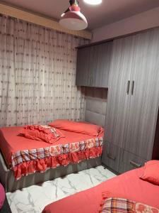 1 dormitorio con 2 camas, armarios y sábanas rojas en بورتو سعيد, en `Ezbet Shalabi el-Rûdi