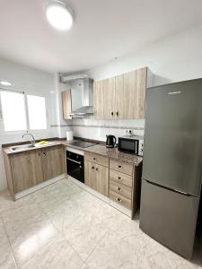 Una cocina con gabinetes de madera y un refrigerador de acero inoxidable. en Centro Apartamentos, en Alicante