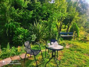 a table and chairs in a garden with a bench at Grandmother Naziko in Vani