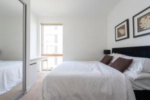 Habitación blanca con cama y espejo en Luxury Apartment Canning Town en Londres