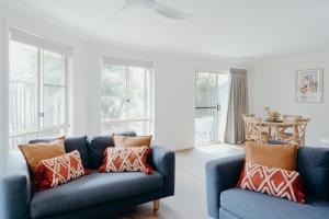 a living room with two blue couches and windows at Bayside Court Apartments in Byron Bay