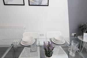 a glass table with white dishes and purple flowers on it at Amazing - 1BDR - Free Street Parking in Wolverhampton