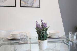 a glass table with a vase with purple flowers on it at Amazing - 1BDR - Free Street Parking in Wolverhampton