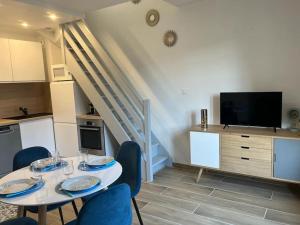 ein Wohnzimmer mit einem Tisch und Stühlen sowie einem TV in der Unterkunft Charmant Duplex, 300 m de la mer in Courseulles-sur-Mer