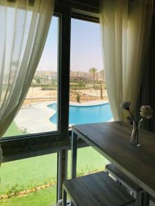 a table and a window with a view of a pool at غرفة فندقية في جولف بورتو مارينا in El Alamein