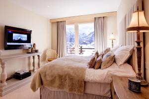 a bedroom with a bed with a television and a window at Chalet Grace in Zermatt