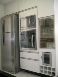 a kitchen with a stainless steel refrigerator and microwave at APTO FRENTE TOTAL P/ MAR in Guarujá