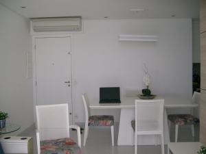 a white table and chairs with a laptop on it at APTO FRENTE TOTAL P/ MAR in Guarujá