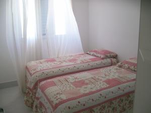 two beds in a small room with a window at APTO FRENTE TOTAL P/ MAR in Guarujá