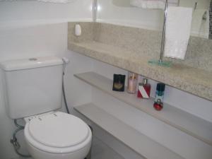 a white bathroom with a toilet and a shelf at APTO FRENTE TOTAL P/ MAR in Guarujá +8 photos