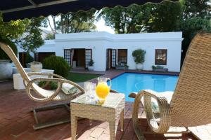 a glass of orange juice sitting on a table next to two chairs at Constantia Garden Suites in Cape Town