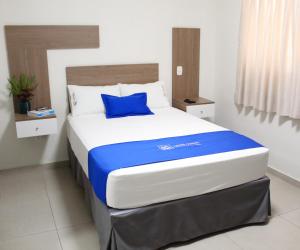Una cama en una habitación con una almohada azul. en Hotel Luxotel Chincha, en Chincha Alta
