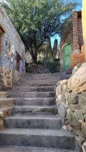 a set of stone stairs in front of a building with a green door at Pacha Cuty Hostel in Amaichá del Valle