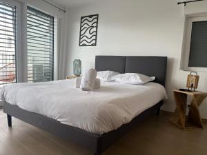 Un dormitorio con una cama grande con sábanas y almohadas blancas. en ENTRE NOUS CITY, en Annecy