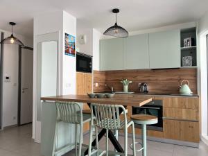una cocina con armarios blancos y una mesa y sillas de madera. en ENTRE NOUS CITY, en Annecy