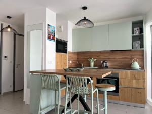 a kitchen with white cabinets and a wooden table and chairs at ENTRE NOUS CITY in Annecy
