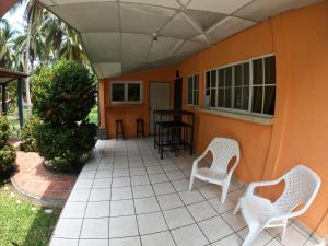 un patio con 2 sillas blancas y una mesa en SALIMAR - Barra de Santiago, en Barra de Santiago