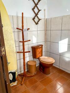 ein Bad mit einem WC und einem Surfbrett an der Wand in der Unterkunft Guest House do Magoo in Arraial do Cabo