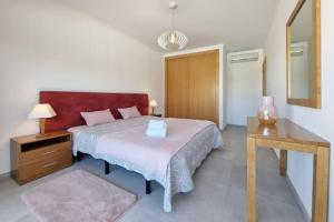 Schlafzimmer mit einem Bett, einem Tisch und einem Spiegel in der Unterkunft Cozy Corcovada T1 in Albufeira