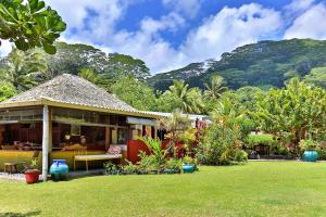 a house with a green yard with mountains in the background at TAHITI - Fare Te Pari in Mariuti