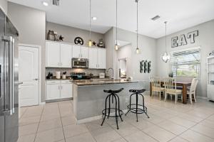 una cocina con armarios blancos y una mesa con sillas. en Beautiful Cape Coral Oasis! King Bed, BBQ, Heated Pool, PVT Yard & Much More! en Cape Coral