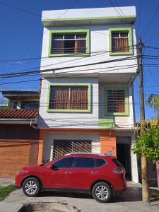 un coche rojo estacionado frente a una casa en 102 RV APARTMENTS IQUITOS-APARTAMENTO FAMILIAR CON PISCINA en Iquitos