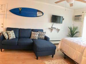 Jonathan's Ocean Front Studio Suites Hampton Beach! في هامبتون: غرفة معيشة مع أريكة زرقاء وطاولة تزلج على الحائط