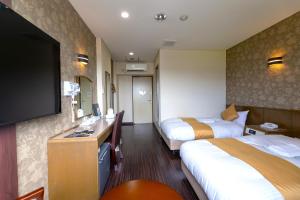a hotel room with two beds and a flat screen tv at セントラルホテル高萩 in Takahagi