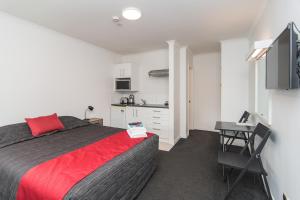 a bedroom with a large bed and a kitchen at The Hibernian Studio Apartments - 4 Latter Street in Timaru
