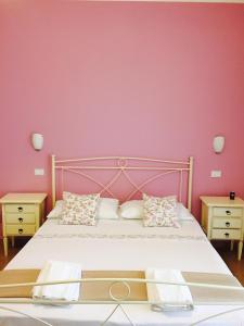 a bedroom with a bed with a pink wall at B&B Zahir in Castro di Lecce