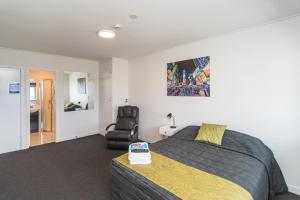 a bedroom with a bed and a chair at The Hibernian Studio Apartments - 4 Latter Street in Timaru