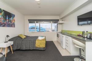 1 dormitorio con cama, escritorio y lavamanos en The Hibernian Studio Apartments - 4 Latter Street, en Timaru
