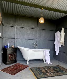a bath tub in a bathroom with a gray wall at Thistle and Pine Cottage Farmstay in Tauranga