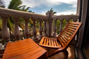 un banco de madera sentado en un balcón con palmeras en Margarita del Sol Hotel Costa Maya, en Mahahual
