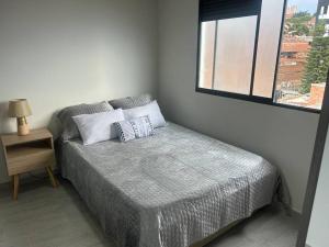 Dormitorio pequeño con cama y ventana en Medellin Hermoso apartamento, en Medellín