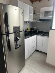 una nevera de acero inoxidable en una cocina con armarios blancos en Medellin Hermoso apartamento, en Medellín